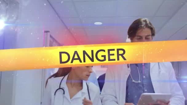 言葉のアニメーション危険性 ウイルス 病院で働く医師の上に危険サイレンと黄色のテープに黒い文字で書かれた検疫 コロナウイルスCovid 19拡散を背景にホールを歩く — ストック動画
