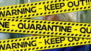 Bu kelimelerin animasyonu, karantinayı sarı ve siyah bantlara yazılı olarak, Coronavirus Covid-19 'un, arka planda bir hastane odasında oturan yaşlı bir kadın hastaya yayıldığı siyah bantlarla uzak tutar.. 