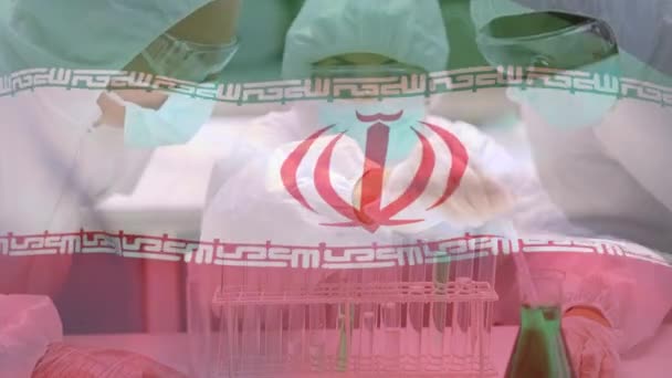 イランの旗のアニメーション コロナウイルスCovid 19は バックグラウンドで顔マスク 保護メガネや外科手袋を身に着けているピペットを使用して研究室で働く科学者の医師に広がって — ストック動画