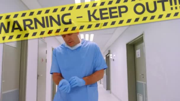 言葉のアニメーション警告は バックグラウンドで病院のホールを歩く男性と女性の医師の上に黄色と黒のテープに黒の文字で書かれた隔離を保つ — ストック動画