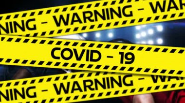 Coronavirus Covid-19 'un iki ragbi oyuncusunun birbirine arka planda başlarıyla vurduğu siyah ve sarı bantlı Uyarı Covid-19 kelimelerinin animasyonu..
