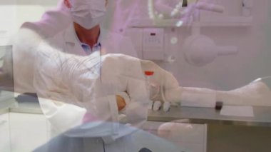 Yüz maskesi takan bir kadın doktorun animasyonu, hastane odasında dikilip, yaşlı bir insanın arka plandaki saate baktığı kamera görüntüsü. Halk sağlığı salgını Coronavirus Covid 19 salgın konsepti dijital bileşik.