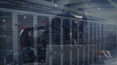 Kapüşonlu bir adamın güneş gözlüğü ve yüz maskesi takarak bilgisayarı hacklemesi, veri işleme ve dijital bilginin sunucu odasındaki ağ üzerinden yüzey üzerinde ışık izleri parlaması.. 