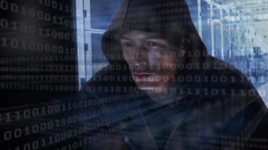 Kapüşonlu bir adamın bilgisayarı hacklemesi, ikili kodlama ve veri işleme ve bilgisayar sunucu ağı üzerinden yüzey üzerinde ışık izleri parlayan bir sunucu odasındaki dijital bilgi akışı