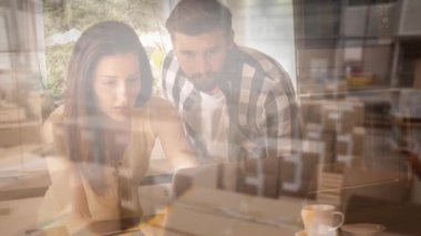 Kafkasyalı bir çiftin arka plandaki depoda dizüstü bilgisayar kullanırken görüntüsü. Karantina karantinasında sosyal uzaklık ve kişisel izolasyon dijital kompozit.