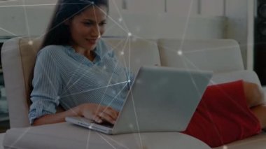 Kanepede oturan, dizüstü bilgisayar kullanan, birbirine bağlı noktalardan oluşan beyaz bir ağ üzerinden kredi kartı tutan ve kameraya doğru giden melez bir kadının animasyonu.. 