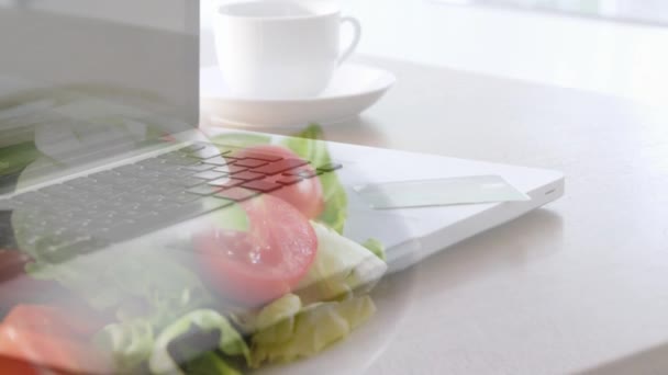 Animáció egy laptopról, ahogy egy asztalon áll egy szendvics és egy saláta felett, ami egy tányéron fekszik a háttérben. Társadalmi távolság és elszigeteltség a karanténban digitális kompozit.