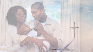 Christian Cross 'un animasyonu, arka planda mavi gökyüzünde parlayan bulutları ve güneşi kucaklayan ve besleyen mutlu çiftin üzerinden geçiyor. Paskalya dini kavramı dijital kompozit.