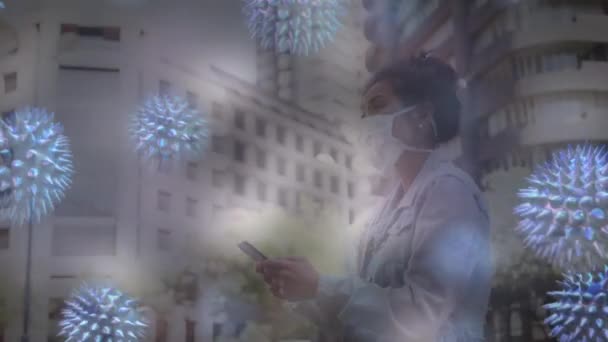 用智能手机在城市街道上戴口罩的妇女身上散播的巨病毒和Coronavirus Covid 19细胞的动画 — 图库视频影像