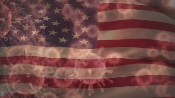 移動する米国の国旗の上に広がっているマクロコロナウイルスCovid 19細胞のアニメーション アメリカの医療公衆衛生パンデミックコロナウイルスCovid 19の発生隔離ロックダウンコンセプトデジタル複合体 — ストック動画