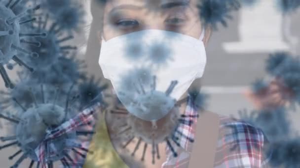 Animation de cellules de macro coronavirus Covid-19 se répandant sur une femme métisse portant un masque facial debout dans une rue de la ville regardant droit devant la caméra . 