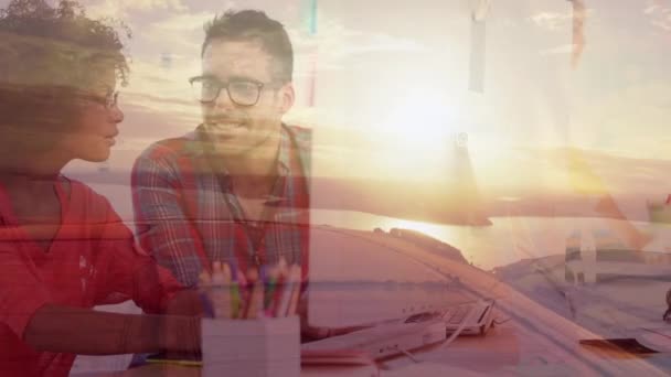 Animation d'un homme d'affaires et d'une femme d'affaires lors d'une réunion de remue-méninges, travaillant ensemble à l'aide d'un ordinateur au bureau avec coucher de soleil et bord de mer. Business teamwork croissance succès concept digital composite .