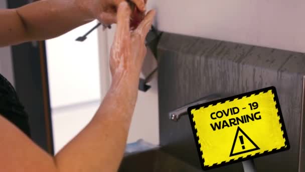 コヴィト19という言葉のアニメーション背景に手を洗う人の上に黄色と黒の看板に書かれた警告 世界的なパンデミックコロナウイルスCovid 19感染症の社会的距離と隔離ロックダウン概念における自己分離デジタル複合体 — ストック動画