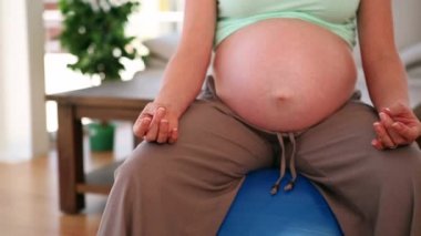 Kelimelerin animasyonu # evde beyaz harflerle yazılır hamile bir kadının orta kısmında İsviçre topunda yoga yapan bir kadının evinde.. 