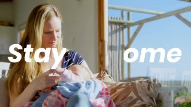 Beyaz bir kadının bebeği tutması üzerine yazılan sözler evde kalacak. Halk sağlığı salgını Coronavirüs Covid 19 sosyal uzaklık ve karantina tecrit konsepti dijital kompozit