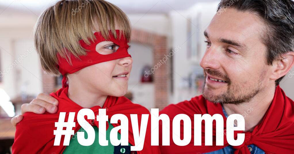 The words #Stayhome with a Caucasian man and his son wearing capes. Public health pandemic coronavirus Covid 19 social distancing and self isolation in quarantine lockdown concept