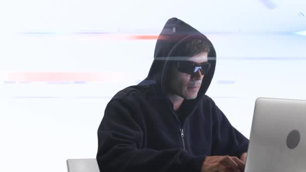 ノートパソコンで作業する黒いフードとサングラスを身に着けている白人男性コンピュータハッカーのアニメーション 白い背景 インターネットサイバー犯罪の概念 デジタル複合体 — ストック動画