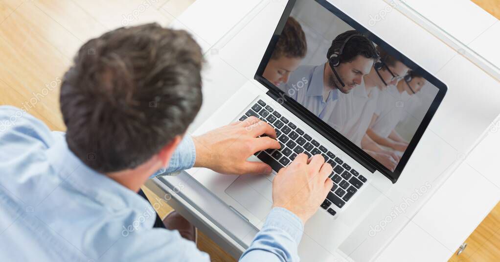 Man using a laptop with group of multi ethnic coworkers in their offices, having a video meeting and interacting online, social distancing and self isolation during lockdown.