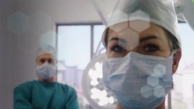 Ameliyat odasında kollarını kavuşturan iki doktorun üzerinde ışıldayan ışınların canlandırması. Dijital olarak üretilen küresel koronavirüs Covid 19 salgın konsepti.