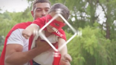 Sosyal uzaklık animasyonu ve Covid-19 mesajı bir meydanda çakıyor. Beyaz adam kızını tutuyor, bahçede oynuyor. Coronavirus Covid-19 pandemik konsept dijital bileşik