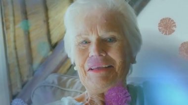 Makro Covid-19 hücrelerinin animasyonu kameraya bakan yaşlı beyaz bir kadının üzerinde yüzüyor. Coronavirus Covid-19 pandemik konsept dijital bileşik