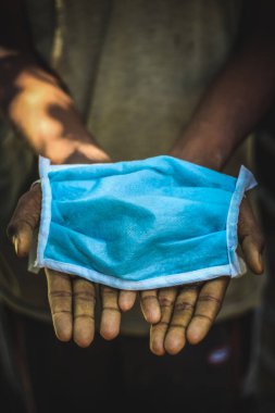 Korunma maskesi. Korona virüsüne karşı el ele tutuşan adamlar. Enfeksiyon maskesi, sağlık konsepti. Mavi yüz maskesi elinde