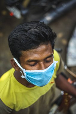 Bulaşıcı hastalıklara karşı koruma, koronavirüs. Enfeksiyonu önlemek için hijyenik maske takan adam, 2020 'deki grip gibi hava yoluyla bulaşan solunum hastalığı. Açık hava çekimi izole edildi. Asyalı genç adam soğuk almış ve mavi maske takıyor.