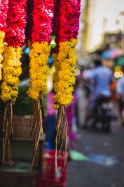 Kırmızı ve sarı çiçekli çelenkler. Çiçek tezgahı tapınak ve evlilik işlevleri için çelenk satıyor. Güney Hindistan pazarında çiçek satmak.