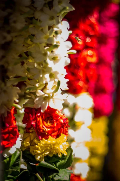 Garlands of red and yellow flowers. Flower stall selling garlands for temple and marriage functions. Selling flowers Garlands on south indian market.