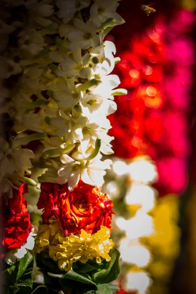 Garlands of red and yellow flowers. Flower stall selling garlands for temple and marriage functions. Selling flowers Garlands on south indian market.