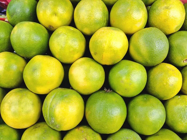 Selling Juicy fresh Green Oranges closeup. Wholesale market. Green Oranges in a box. Selling crops on the market. Natural, healthy, vitamin-rich foods. Food for health. High Vitamin-C fruits