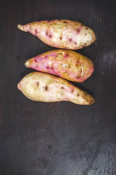 Raw sweet potatoes on wooden background closeup. sweet potato on wooden surface. Ipomoea batatas or Shakarkandi