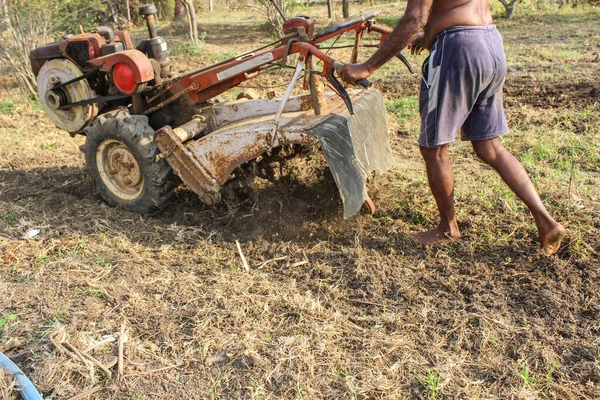 Farmer handing Mini Tractor for planting root crops in the countryside agriculture. Plowing a field with mini tractor. Rough wheel with a plow close-up on the background of the land