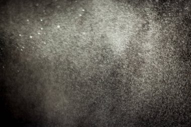 Şişeden su püskürtme. Siyah arkaplanda izole edilmiş su damlalarına yakın çekim.