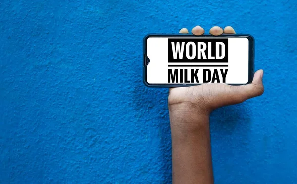 1st June - World Milk Day wording on the smart phone mobile screen with isolated on blue background. World Milk Day wording.