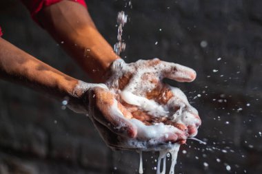 Ellerini yıkıyor. Evdeki bahçede ellerini yıkayan bir adam. Corona virüsü salgını önleme sabunla, sıcak suyla, ovalayarak ve tırnaklarla sık sık yıkanarak ellerini yıkar. Hijyen & Temizleyici Eller.