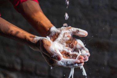 Ellerini yıkıyor. Evdeki bahçede ellerini yıkayan bir adam. Corona virüsü salgını önleme sabunla, sıcak suyla, ovalayarak ve tırnaklarla sık sık yıkanarak ellerini yıkar. Hijyen & Temizleyici Eller.