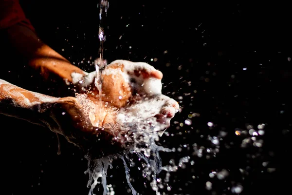 Washing hands.Man washing his hands isolated on black background.Corona virus pandemic prevention wash hands with soap warm water & rubbing nails & fingers washing frequently.Hygiene & Cleaning Hands.