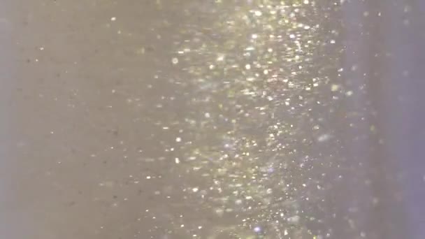 Крупним планом блиск плаває в горілці барвиста золота фарба змішування у водяному чорнилі — стокове відео