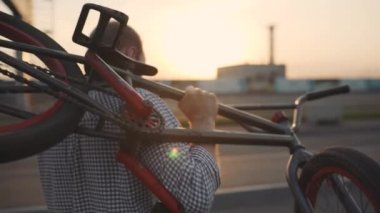 Ağır çekim adamı kırık bmx bisiklet taşıyor ve telefonda konuşuyor.