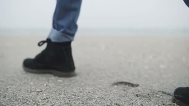 Крупним планом ноги молодого чоловіка, що йде один на пляжі — стокове відео