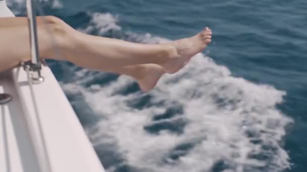Female legs hanging from the yacht — Stock Video
