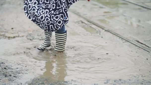 Girl in rubber boots runs and jumps in a puddle — Stock Video