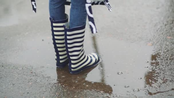 Girl in rubber boots runs and jumps in a puddle — Stock Video