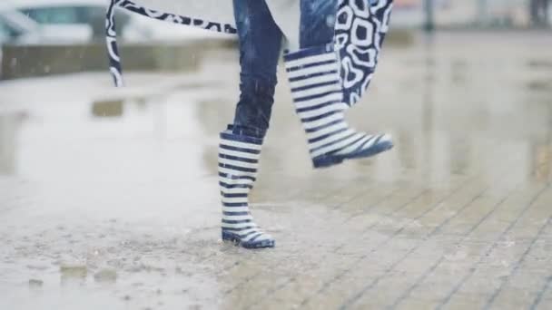 Girl in rubber boots runs and jumps in a puddle — Stock Video