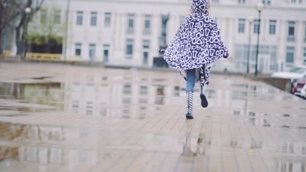 Girl in rubber boots runs and jumps in a puddle — Stock Video