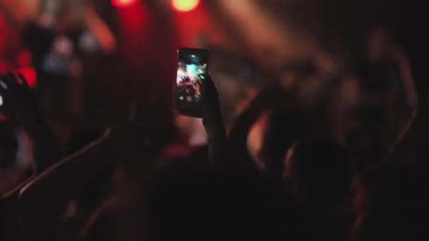 Руки в толпе держат смартфон и снимают музыкальное выступление на сцене — стоковое видео