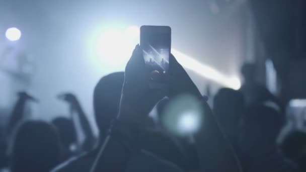 관중들 사이에서 스마트폰을 들고 무대에서 음악 공연을 하는 사람들의 손에 손을 잡고 — 비디오
