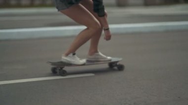 Genç bayan hippi kaykayla sokakta geziyor.