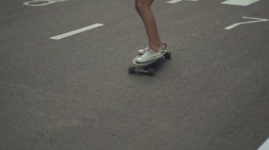 Genç bayan hippi kaykayla sokakta geziyor.